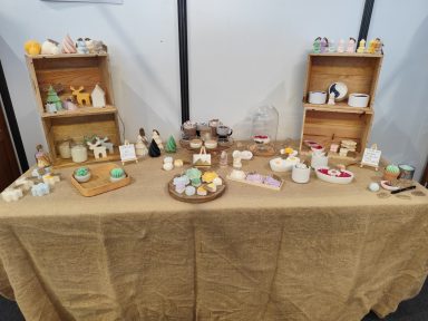 Table décorée avec des bougies, figurines et objets artisanaux sur étagères en bois.